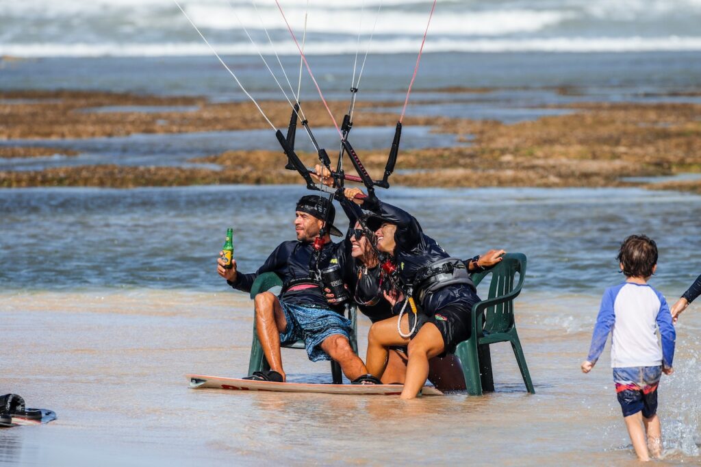 grupo de amigos tomando una birra aprendiendo a maniobrar el kite